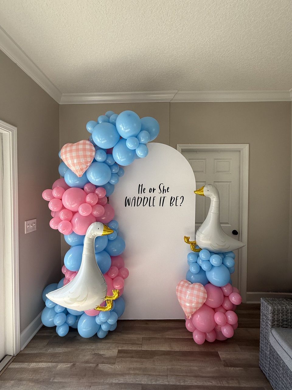 Blue and pink gender-reveal backdrop with goose balloons