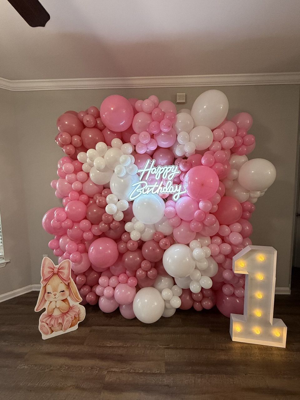Pink and white balloon wall with a light-up number 1