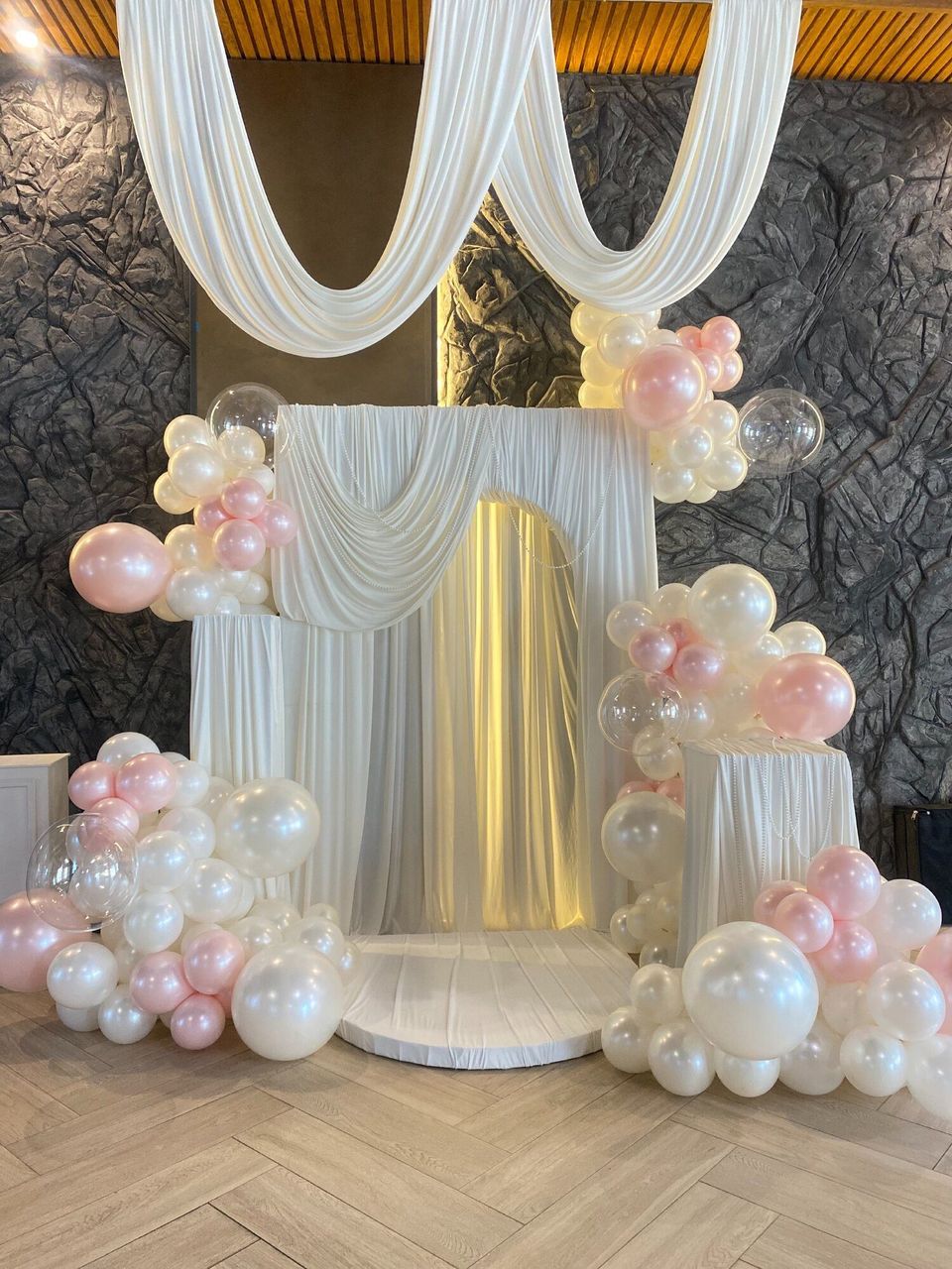 White draped backdrop framed with pastel balloons