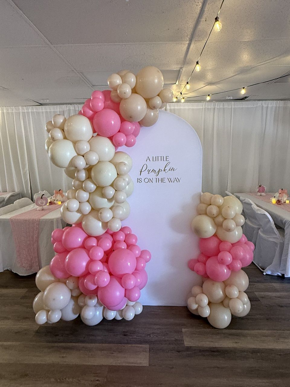 Pink and cream balloon arch around a round backdrop