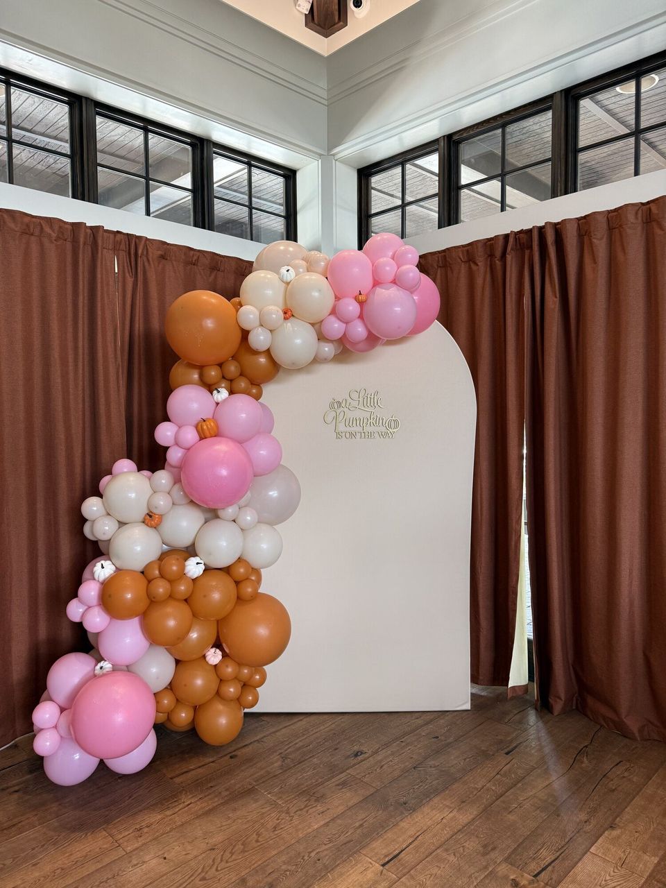 Pink and orange balloon garland on an arched backdrop