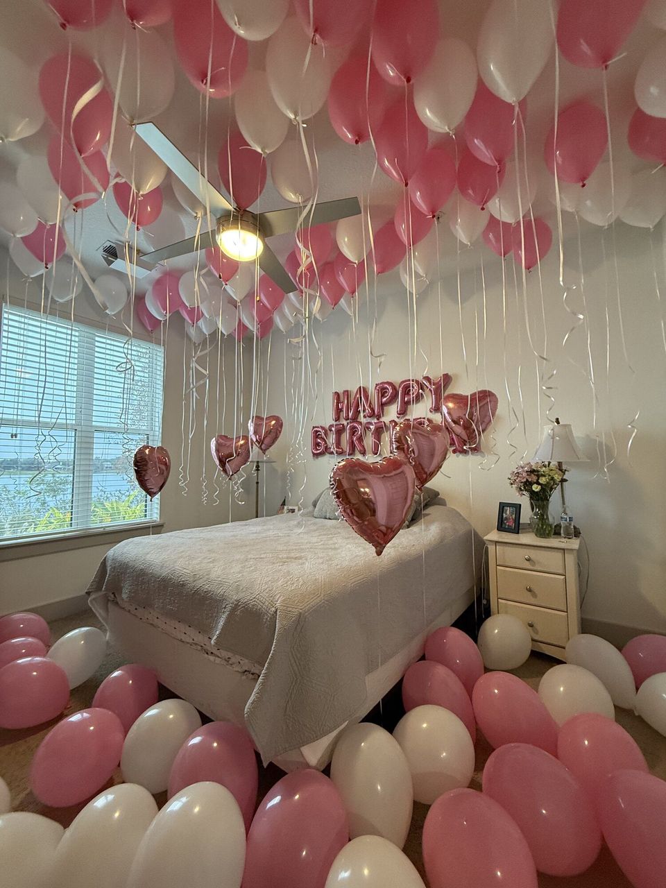 Bedroom decorated with pink balloons and a birthday sign